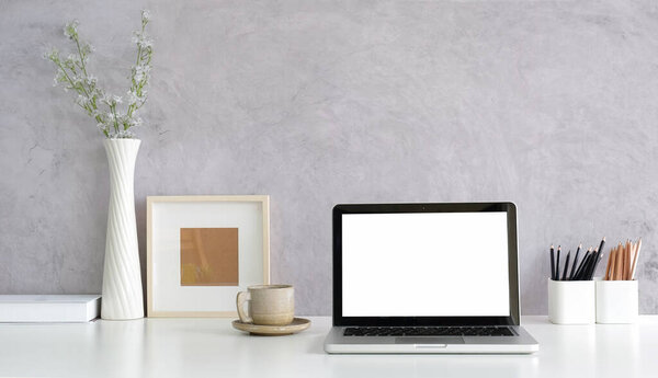 Modern workplace, computer laptop and supplies on white table with loft wall.