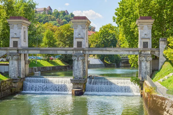 Arka plandaki Ljubljanica Nehri Bariyeri, Bölünme ve şehir kalesi. Slovenya 'nın başkenti Ljubljana' daki Ljubljanica Nehri 'nde 1930' larda Slovanyalı mimar Joe Plenik tarafından açılan bir geçit ve zafer kemeri..