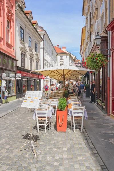 Ljubljana, Slovenya - 15 Ağustos 2018: Eski kentteki Stari caddesini güneş gözlüklü turistler ve restoran masaları paylaşıyor