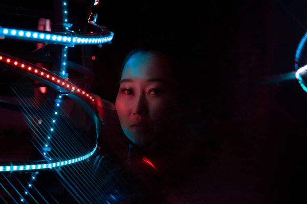 Portrait of a girl in the style of cyberpunk, using optical refraction using a prism. Night city, the girl's gaze is directed directly at the camera, her hand is leaning against the light source