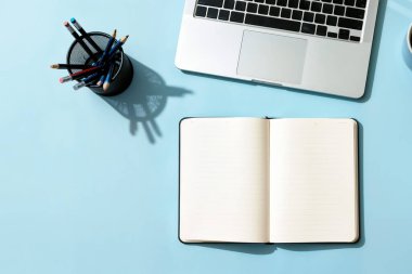 Not Defterini Dizüstü bilgisayar ve Kalem Tutucu ile Mavi Masa 'da Aç