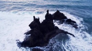 Video con dron en atardecer de las rocas y olas rompiendo se sobre ellas en la playa de Benijo Islas Canarias, Espaa 