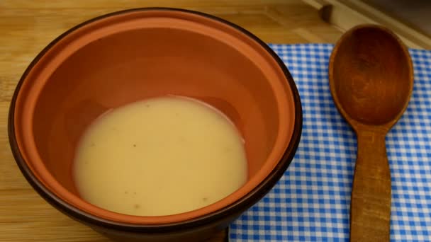 A sopa de ervilha creme é derramada em tigela marrom e polvilhada com ervas picadas e croutons fritos. Conceito de comida vegetariana saudável. Close-up. — Vídeo de Stock