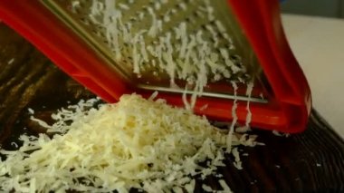 Şef peynir rendeliyor pizza, makarna ya da metal rendeyle siyah kesim tahtasında başka bir yemek için. Bir yığın rendelenmiş peynir. Ev yemeği..