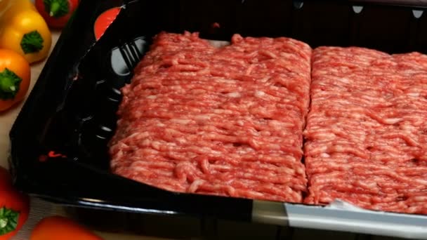 Syrové mleté maso v plastovém obalu a barevná zelenina leží na kuchyňském stole. — Stock video