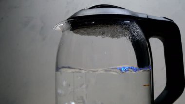 Kabarcıklı su, arka planda şeffaf cam elektrikli su ısıtıcısında kaynıyor. Yakın plan..