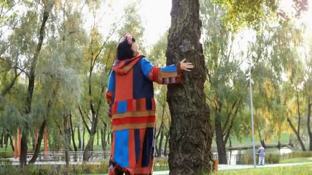 Легендарна доросла жінка кавказької національності ходить по дереву восени і тримає дерево рукою. Підсумок.. — стокове відео