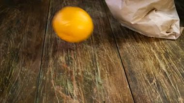 Aşçılık işi. Kağıt torbadan ahşap masaya fırlatılan farklı narenciye meyveleri. Mandalina ve limon. Yakın plan..