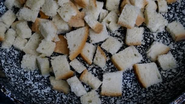 Fatias de pão branco cortadas em cubos, fritas em frigideira e viradas com espátula para fazer croutons. Cozinha caseira. Close-up. — Vídeo de Stock