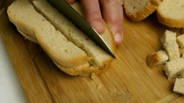 Beyaz ekmek dilimleri, ekmek bıçağı ile küp şeklinde kesilerek tahtadan ekmek ya da çivi yapılır. Ev yapımı mutfak. Yakın plan..