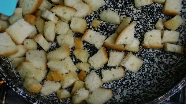 흰 빵 슬라이스를 썰어서 스칼 렛 에 튀긴 다음 스파 툴라 로 뒤집어 크루 톤 을 만들었다. 홈 메이드 주방. 클로즈업. — 비디오