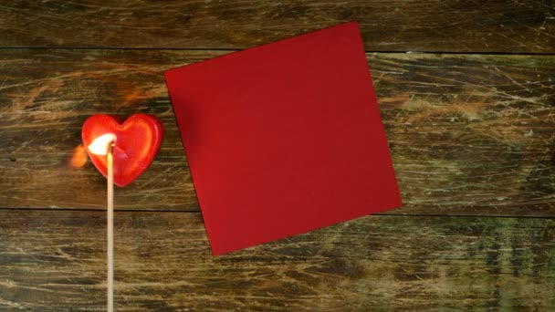 Menselijke handen zetten een kop koffie op een rode servet en zetten een hartvormige kaars in brand. Een romantische dag. Valentijnsdag of vrouwen dag concept. Bovenaanzicht. Plat gelegd. Close-up. — Stockvideo