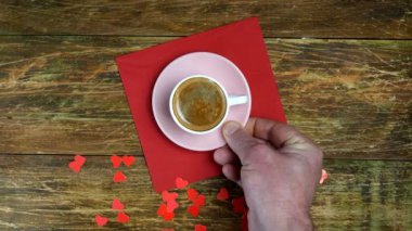 İnsan eli kırmızı peçeteye bir fincan kahve ve oyuncak ayı koyar. Kırmızı kalpler. Romantik bir gün. Sevgililer günü ya da kadınlar günü konsepti. Üst Manzara. Düz yatıyordu. Yakın plan..