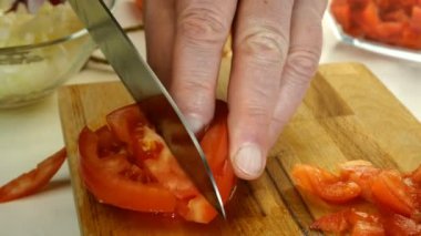 Şef salata için ahşap doğrama tahtasına büyük keskin bir bıçakla domates kesiyor. Sağlıklı beslenme konsepti. Shakshuka tarifi. Yemek pişirme süreci. Yakın plan..