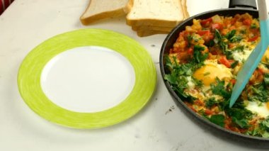 Şef sebze soslu kızarmış yumurta shakshuka tabağına ekliyor. Yahudi ve Arap mutfağı. Shakshuka tarifi. Sağlıklı besleyici kahvaltı. Yakın plan..