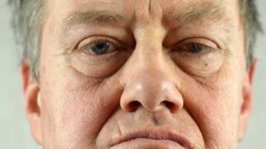 Yetişkin erkeklerin gülümsediği ön portre. Kırışık derili ve gri gözlü, kameraya bakıyor. Seçici yumuşak odaklanma. Yakın plan..