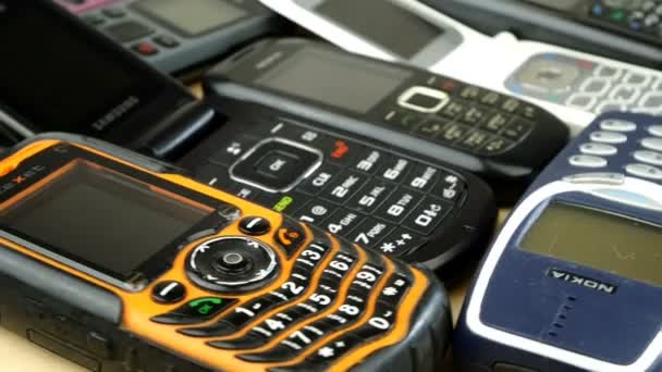 Κίεβο, Ουκρανία, Ιανουάριος 2021: - Πολλά σκονισμένα, παλιά και απαρχαιωμένα, μεταχειρισμένα κινητά τηλέφωνα διαφορετικών εμπορικών σημάτων περιστρέφονται δεξιόστροφα. Αναλογική επικοινωνία. Ηλεκτρονικό πρόβλημα ανακύκλωσης. Κοντινό πλάνο. — Αρχείο Βίντεο