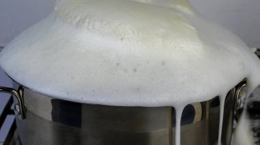 İnek sütü kaynayıp taşar. Kaynayan süt tencereden çıkar. Ocakta süt unuttum. Seçici odaklanma. Yakın plan..