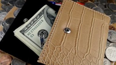 Birkaç yüz Amerikan dolarının ortaya çıktığı ve bir sürü dağınık Amerikan sentinin daire şeklinde döndüğü açık cüzdan. Çantanın altından Amerikan bayrağı görünüyor. Ağır çekim. Yakın plan..
