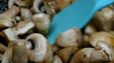 Çiğ, yenilebilir şampiyonlar, dört dilime bölünmüş yemek pişirmek ve lezzetli yemekler yapmak için kızartma tavasıyla spatulaya karıştırılmış. Yakın plan..