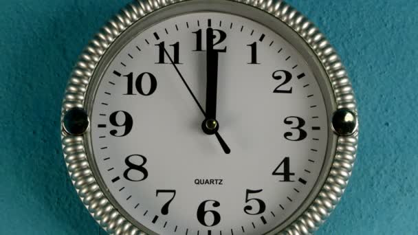 秒針付きクォーツウォールクロックが時計回りに動作します。時計は１２時を示している。古い青い壁に。閉鎖. — ストック動画