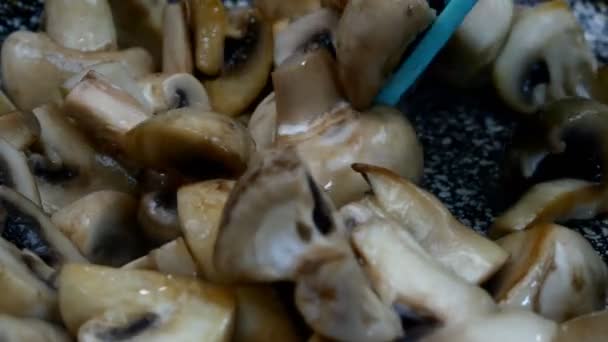 Grands champignons comestibles crus, coupés en quatre tranches mélangeant dans une poêle à frire avec une spatule de cuisine pour la cuisson et la fabrication d'aliments délicieux. Gros plan. — Video