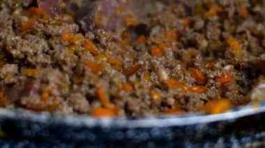 Kızartma tavasına domatesli bolonez sosu, zeytinyağı, otlar, jambon, havuç, kıyma ve iyice karıştır. Geleneksel İtalyan yemekleri. Yakın plan..