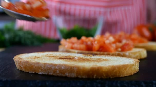 Chef strooit fijn gesneden rode tomaten bovenop geroosterd brood voor het maken van broodjes of bruschetta. Zomer vegetarisch broodje. Selectieve focus. Close-up. — Stockvideo