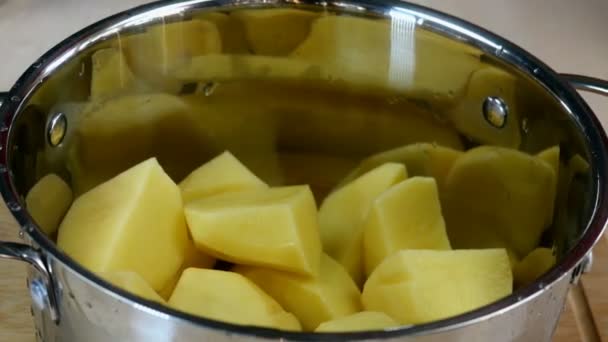 Şef büyük bir parça çiğ patatesi tencereye koyar ve patates püresi veya diğer yiyecekler için temiz soğuk suyla doldurur. Ev mutfağı tarifi. Yakın plan.. — Stok video