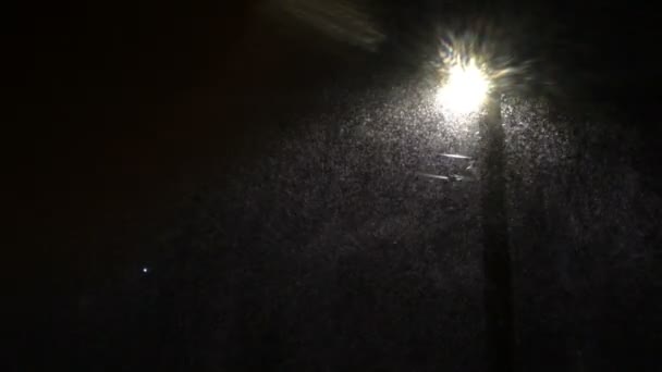 Sneeuw valt 's nachts over straatlamp tijdens zware sneeuwval. Wintersneeuwstorm, kerststemming. Close-up. — Stockvideo