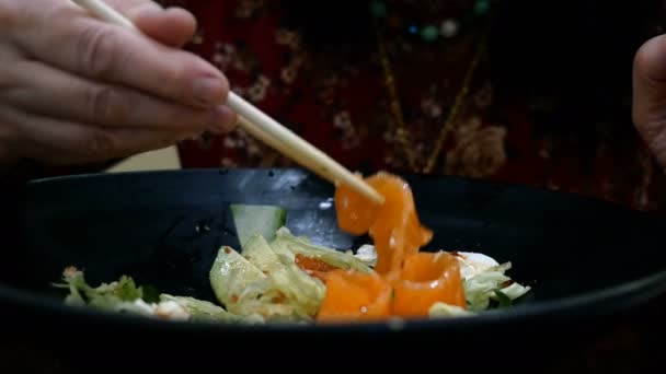 Женщина ест свежий вкусный салат с овощами, соленого лосося и сливочного сыра с деревянными палочками. — стоковое видео