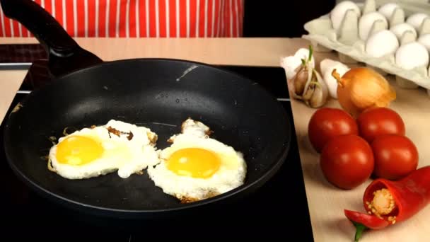 Retourner l'œuf de poulet sur la poêle chaude et cuire les œufs frits. Tomates, poivre et ail. — Video