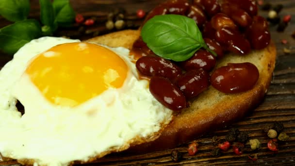 Cocción de sándwich o bruschetta con frijoles rojos y huevo frito sobre pan tostado. — Vídeo de stock