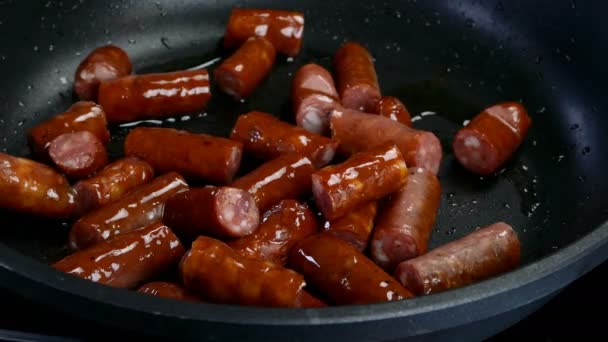 Pyszne tłuste kiełbaski myśliwskie, pokrojone na kawałki, smażone są na patelni w oleju roślinnym. Szybkie pożywne jedzenie. Kuchnia. Zbliżenie. — Wideo stockowe