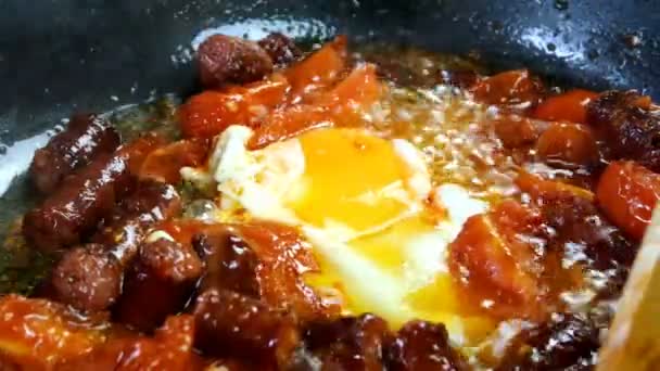 Delicious fatty hunting sausages, chicken egg and sliced tomatoes are fried in frying pan in vegetable oil. Fast nutritious food. Home kitchen. Close-up. — Stock Video