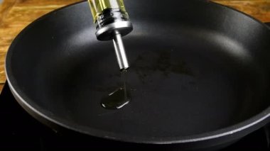 Aşçı yemek pişirmek için tavaya ayçiçeği yağı ya da zeytinyağı döker. Yakın plan..