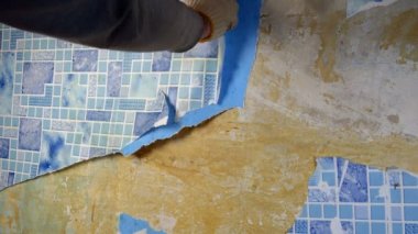 Eski evdeki onarımlar için yıpranmış ve çatlamış duvar kağıtlarını yırtan biri. Yakın plan veya orta plan.