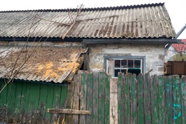 Yeşil ahşap çitlerin arkasındaki köyde terk edilmiş tuğladan bir ev cephesi. Yakın plan. Açık havada..