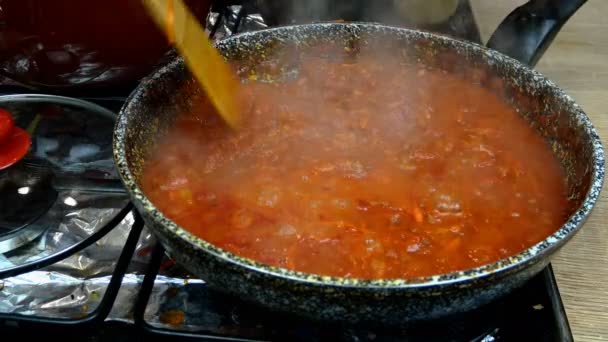 Saus tomat gurih dengan sayuran untuk pasta atau pizza, mendidih dalam penggorengan di atas kompor gas. Resep untuk membuat pasta atau tagliatelle di dapur rumah. Close-up. — Stok Video