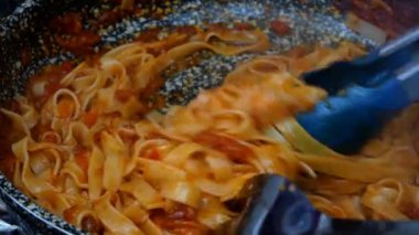 Lezzetli domates sosuyla sebzeleri karıştırılmış spagetti. Gaz sobasında tavada kaynatılmış. Ev mutfağında makarna ya da tagliatelle tarifi. Yakın plan..