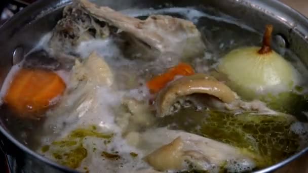 Koka i kokande vatten fet kyckling buljong från kött och ben med lök och morötter för soppa beredning, i kastrull. Hemkök. Närbild. — Stockvideo