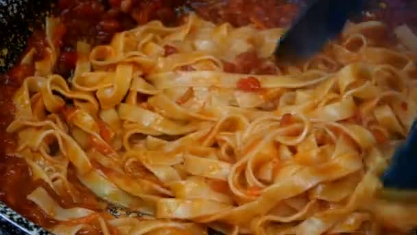 Spageti dicampur dengan saus tomat gurih dengan sayuran, mendidih dalam penggorengan pada kompor gas. Resep untuk membuat pasta atau tagliatelle di dapur rumah. Close-up. — Stok Video