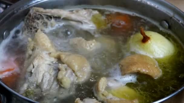 सूप तयार करण्यासाठी मांस आणि हाडांमधून उकळत्या पाण्यात फॅटी चिकन बुरशी शिजवणे, सॉसपॅनमध्ये कांदे आणि गाजर. घरगुती स्वयंपाकघर. बंद करा . — स्टॉक व्हिडिओ