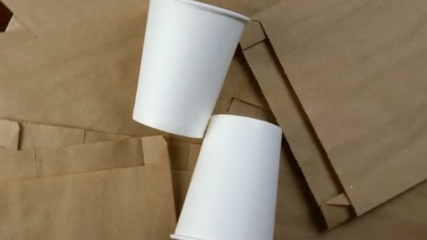 Paquete de papel vacío, embalaje biodegradable desechable ecológico para mercancías y taza de papel vacía. Rota en círculo. Fondo ecológico. Vista superior. Primer plano. — Vídeo de stock