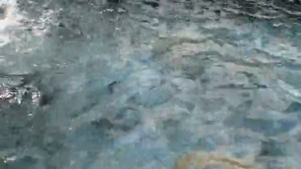 Las olas de agua transparente divergen en la superficie de agua limpia en el río, estanque o piscina con salpicaduras durante el día. Primer plano. — Vídeo de stock