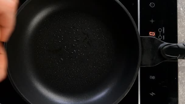 Preparación de huevos fritos en sartén para el desayuno en la cocina eléctrica en el hogar o restaurante. Huevo de pollo crudo roto cae en sartén caliente. Vista superior. Comida de arriba abajo. Primer plano. — Vídeos de Stock