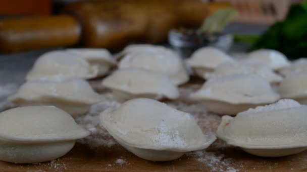 Rijen bevroren rauwe pelmeni knoedels gevuld met gehakt op snijplank. Heerlijke traditionele handgemaakte gerechten op de huiselijke keuken. Aziatische en Russische keuken. Dolly neergeschoten. Close-up. — Stockvideo