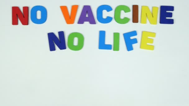 La main humaine plie inscription pas de vaccin pas de vie à partir de lettres multicolores sur fond blanc. Concept de vaccination comme sauver votre vie pendant l'épidémie de coronavirus. Ampoule et seringue. — Video