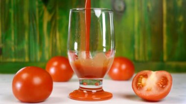 Taze olgun domateslerin yanında boş şeffaf bardağa taze domates suyu döktü. Bol vitaminli sağlıklı vejetaryen içeceği. Seçici odak.