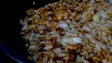 İnce doğranmış soğanlar haşlanmış sebze ya da zeytinyağında tavada kızartılır. Ev mutfağı. Dolly vurdu. Yakın plan..